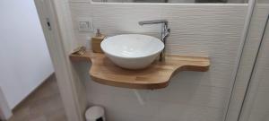 a bathroom with a white sink on a wooden shelf at Il fiore di loto in San Felice Circeo