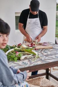 un homme préparant des légumes sur une table avec un garçon dans l'établissement Masseria Prosperi, à Alimini