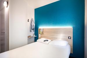 una camera con un letto bianco e una parete blu di hotelF1 Fréjus Roquebrune sur Argens a Roquebrune-sur Argens