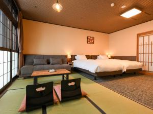 een hotelkamer met een bed en een bank bij Kutsurogijuku Chiyotaki in Aizuwakamatsu