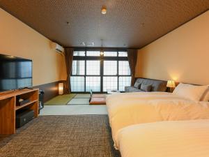 een hotelkamer met 2 bedden en een flatscreen-tv bij Kutsurogijuku Chiyotaki in Aizuwakamatsu