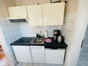 a small kitchen with white cabinets and a sink at Exclusives Apartment im Herzen von Westerland in Westerland (Sylt)