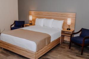 1 dormitorio con 1 cama y 2 sillas azules en Hotel Dunas Near Consulate, en Ciudad Juárez