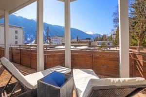 a balcony with a table and chairs on a deck at Hotel Europe in Davos