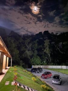 un groupe de voitures garées sur un parking la nuit dans l'établissement Chalés Bem-me-quer Itaipava, à Itaipava