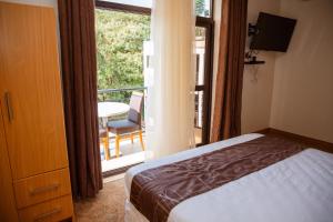 een slaapkamer met een bed en een balkon met een tafel bij Ndaru Luxury Suites in Kigali