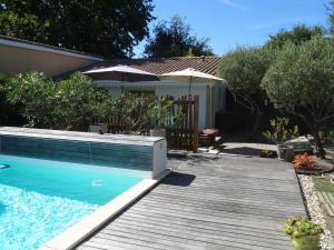 einen Pool mit einer Holzterrasse neben einem Haus in der Unterkunft Cabane Blanche in Andernos-les-Bains