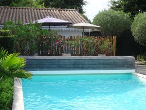 einen Pool im Garten mit Sonnenschirmen in der Unterkunft Cabane Blanche in Andernos-les-Bains