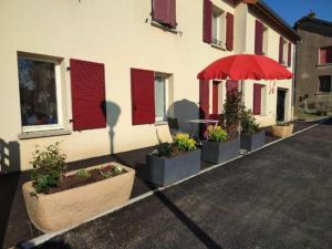 um edifício com um guarda-chuva vermelho e algumas plantas em Gîte cosy à Ville-au-Val, proche Nancy et Metz, randonnées, 1 chambre, parking et terrain privé. - FR-1-584-111 em Ville-au-Val