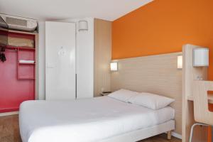 um quarto com uma cama branca e uma parede laranja em Premiere Classe Lyon Est - Bron Eurexpo em Décines-Charpieu