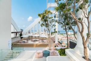 - un balcon avec des canapés et des arbres dans un bâtiment dans l'établissement Arbour Hotel and Residence, à Pattaya