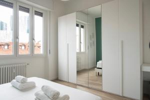 a bedroom with white walls and a large mirror at YouHosty - 25 Aprile 5 in Milan