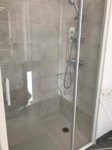 La salle de bains est pourvue d'une douche avec une porte en verre. dans l'établissement APPARTEMENT NEUF ET BIEN SITUE AVEC UN CLASSEMENT, à Saint-Malo