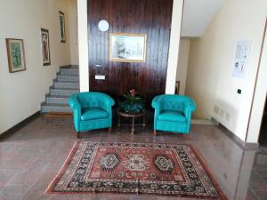 Residence Villa Margherita B&B في Nebbiuno: ممر وبه كرسيين ازرق وسجادة