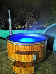 a wooden hot tub with a blue top at night at Pensiunea Mariana in Ocna Şugatag