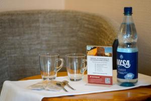 Una botella de agua y dos vasos en una mesa. en Hotel Zur Mühle, en Kappeln