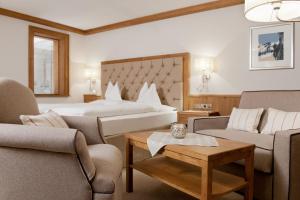 a hotel room with a bed and chairs and a table at Alpen-Wellness Resort Hochfirst in Obergurgl