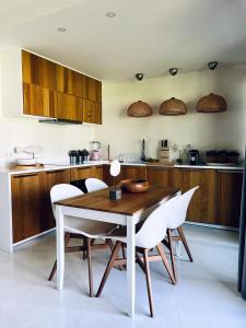 - une cuisine avec une table en bois et des chaises blanches dans l'établissement Beach House Pedras D'el Rei, à Santa Luzia