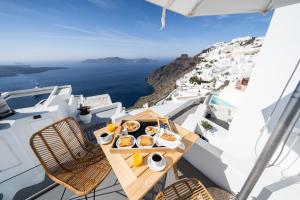 una mesa con comida en el balcón con vistas al océano en Smaro Studios, en Firostefani