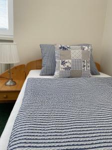 a bed with a blue and white striped sheets and pillows at Penzion Ječmínek in Luhačovice