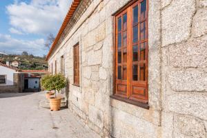 een stenen gebouw met een houten deur en potplanten bij Casa do Boco in Oliveira do Hospital