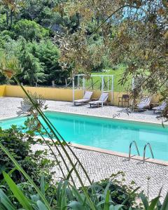 een zwembad met 2 ligstoelen ernaast bij Quinta Da Torre - Óbidos Country House in Óbidos