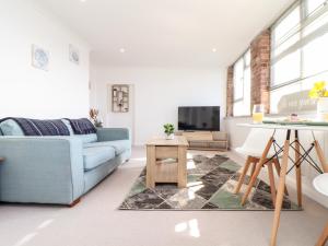 a living room with a blue couch and a tv at Lighthouse Lofts - Godrevy in Camborne