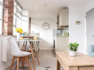 a kitchen with white cabinets and a table with chairs at Lighthouse Lofts - Godrevy in Camborne