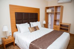 een slaapkamer met een groot wit bed met een houten hoofdeinde bij Ndaru Luxury Suites in Kigali