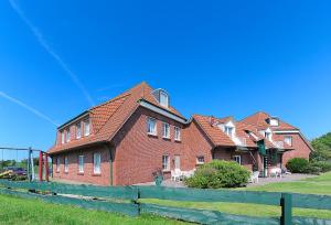 une grande maison en briques avec une clôture devant elle dans l'établissement Ferienhaus Wattn Urlaub, à Bensersiel