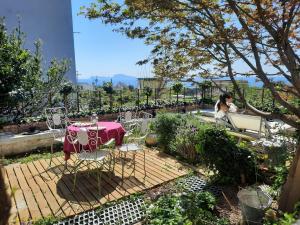 een vrouw aan een tafel in een tuin bij Homes Oasi Posillipo in Napels