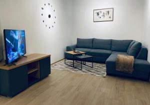 uma sala de estar com um sofá azul e uma televisão em OM Apartment em Podgorica