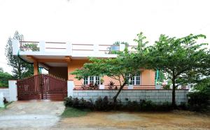 une maison avec une clôture et un arbre devant elle dans l'établissement Srishti Homestay, à Madikeri