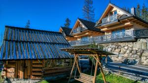 Cette maison en rondins dispose d'une terrasse couverte et d'une balançoire. dans l'établissement Domki na Skałach Centrum Zakopane, à Zakopane