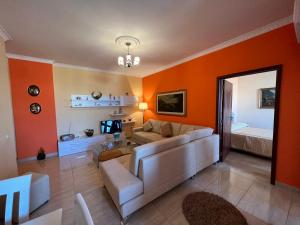 a living room with orange walls and a couch and a bed at City Center Apartment in Shkoder in Shkodër