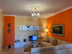 a living room with orange walls and a couch at City Center Apartment in Shkoder in Shkodër