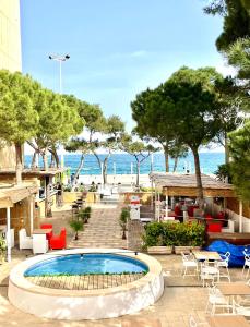 una piscina con tavoli e sedie e la spiaggia di Hotel Venteo a Platja  d'Aro