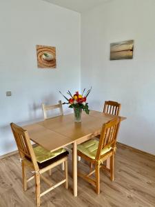 una mesa de madera con sillas y un jarrón de flores. en Gartenapartment Storchenblick, en Weiden am See