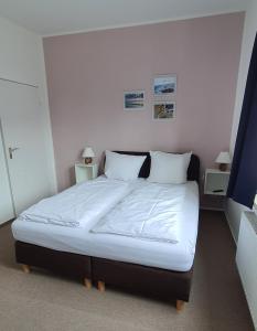 a bedroom with a bed with white sheets and pillows at Gästehaus bed & kitchen in Schleswig