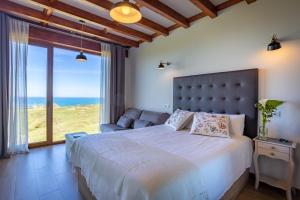 een slaapkamer met een groot bed en uitzicht op de oceaan bij Posada Punta Ballota in Suances