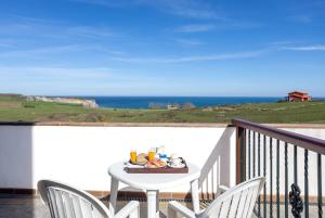 een tafel en stoelen op een balkon met uitzicht op de oceaan bij Posada Punta Ballota in Suances