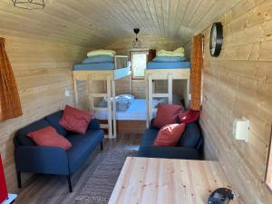 een kamer met 2 bedden en 2 banken in een tiny house bij Pipowagen voor 4 personen in Diever