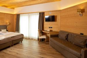 a hotel room with a bed and a couch and a desk at B&B Ecohotel Chalet des Alpes in Livigno