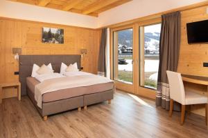 a bedroom with a bed and a desk and a television at B&B Ecohotel Chalet des Alpes in Livigno