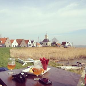 een tafel met twee glazen bier en een bord eten bij Very nice cottage in Durgerdam, with private garden, free parking, pets allowed in Amsterdam