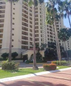 a large building with palm trees in front of it at Paradise apartment, private beach condo Bay View Grand in Puerto Vallarta