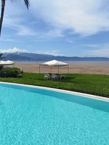 a swimming pool with a table and umbrellas next to a beach at Paradise apartment, private beach condo Bay View Grand in Puerto Vallarta