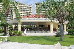 a woman in a white dress standing in front of a building at Paradise apartment, private beach condo Bay View Grand in Puerto Vallarta