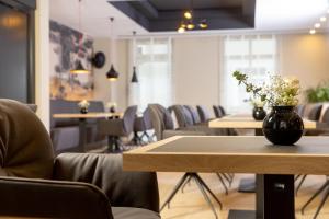 een kamer met tafels en stoelen en een vaas met bloemen op een tafel bij maakt Hotel in Stralsund