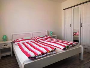 a bed with a red and white striped blanket on it at Ubytování Valentovi in Veľký Meder